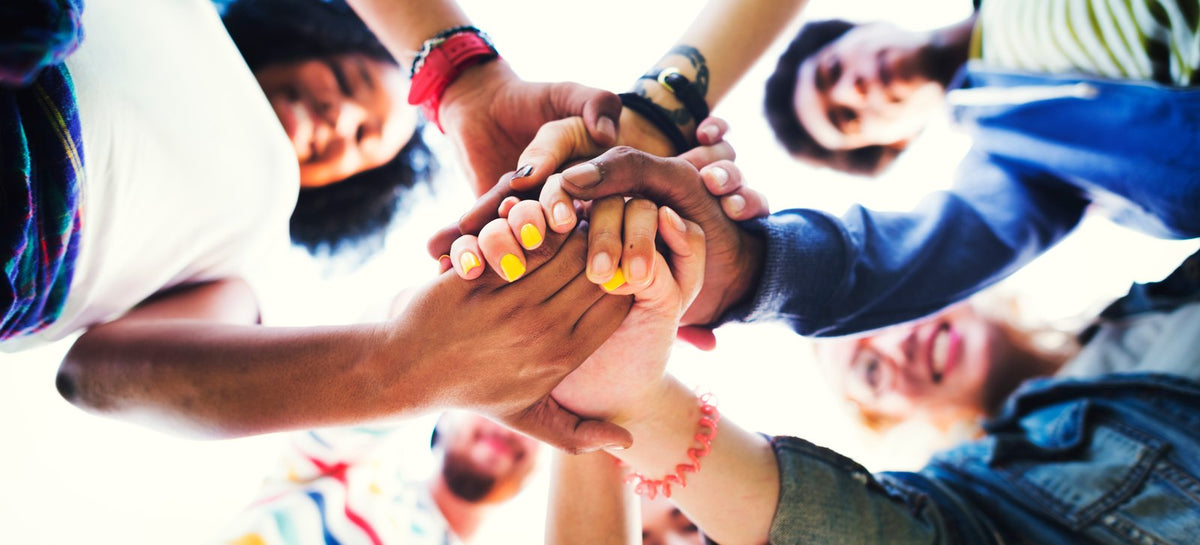 A circle of young people joining hands in the middle
